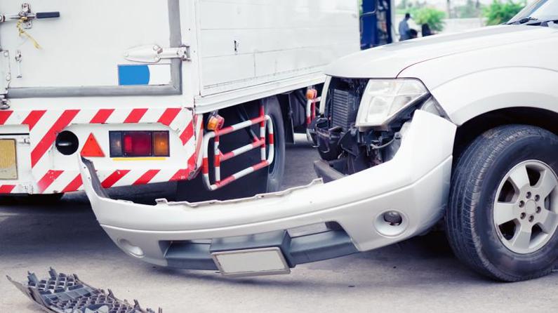 A car with the front bumper knocked off of it in a truck accident