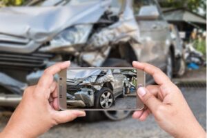 Close up of woman’s hands holding smartphone and taking photo of car accident